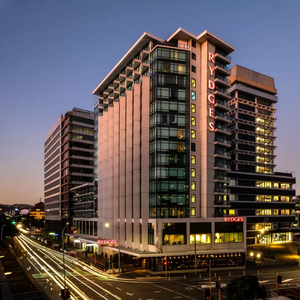 The Rydges Hotel in Wellington at dusk, with long exposure car headlight trails sweeping past the front door. 