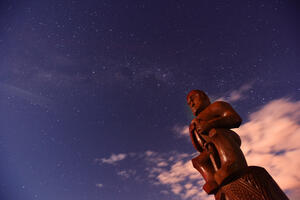 Image of a pou whenua against a starry sky. 