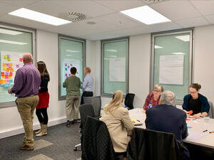 Customers and LINZ staff in a meeting room, talking and writing notes on boards